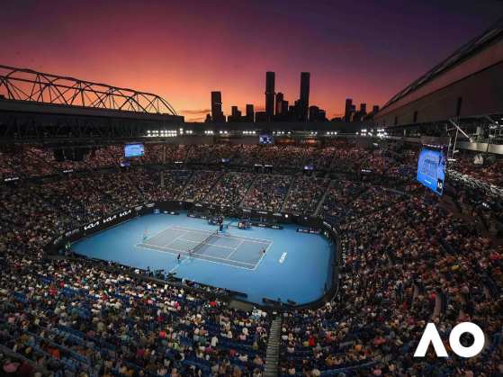 Overhead view of an Australian Open match in a full stadium just after sunset with the Australian Open in the bottom right corner 